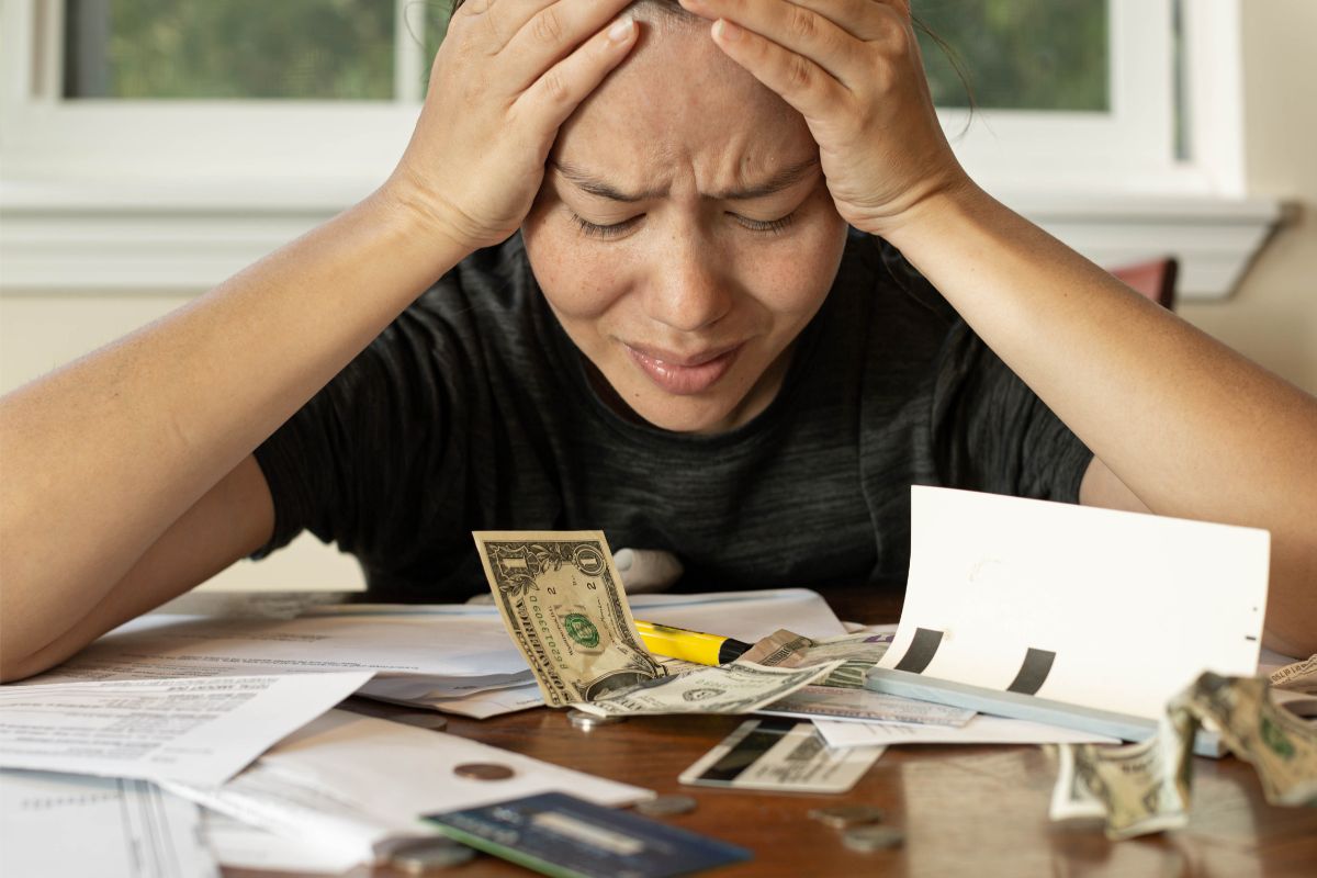 A woman is stressed over bills, showing the financial consequences of untreated addiction.