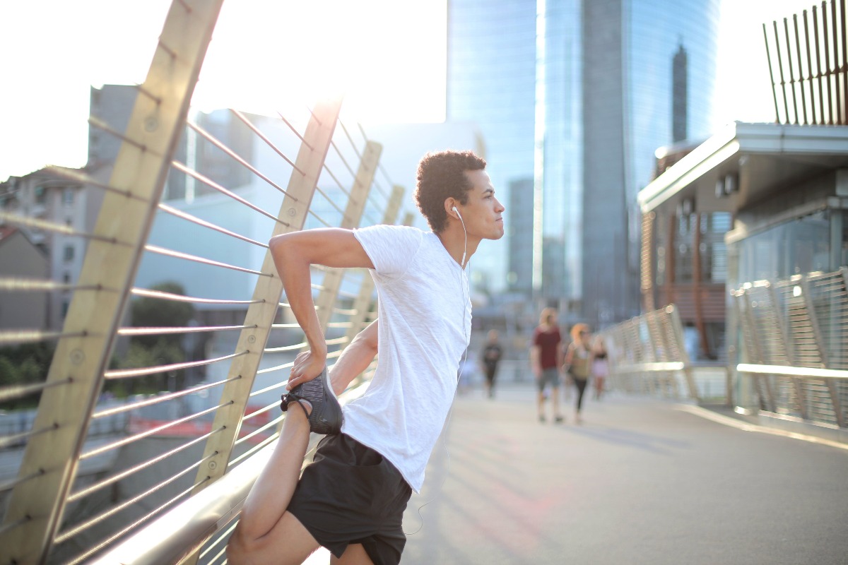 A young man stretches in the city, using exercise as a healthy coping skill for stress and anxiety.